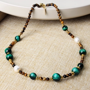 Detail of beaded necklace with tiger eye, green malachite, white pearls, and gold clasp