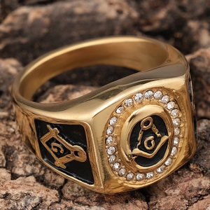 Detailed close-up of a gold Masonic ring with zircon stones on a rustic bark background