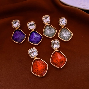Detailed view of geometric resin drop earrings in purple, gray and orange with gold edges