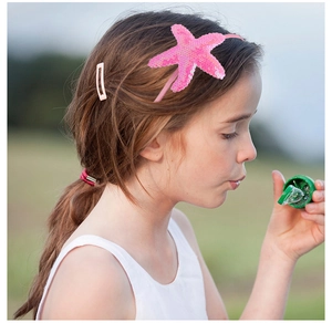 Close-up of a girl wearing a pink sequined starfish headband and hair clip in nature