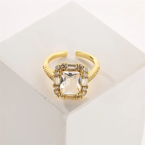 Detail of an adjustable gold ring featuring a large rectangular clear zircon on a white cube