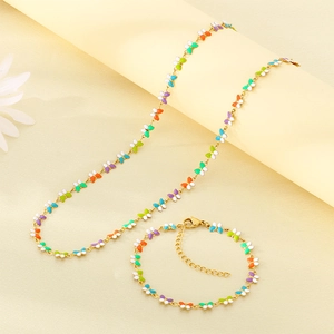 Detalle del conjunto de collar y pulsera de mariposa dorada con alas de esmalte