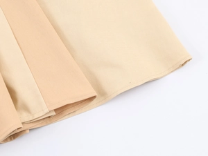 Detail of beige cotton woven fabric showing heavy embroidery and double stitched hemline