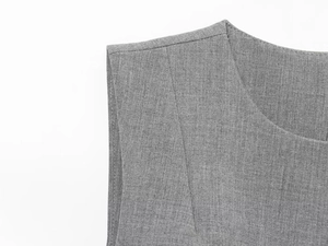Detail of grey satin sleeveless dress showing precise shoulder stitching and twill texture
