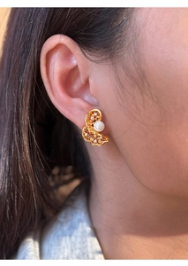 Detailed view of a gold hollow earring with a round pearl and sparkling zircon accents