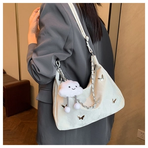 Détail du sac à bandoulière beige matelassé avec papillon argenté et charm nuage doux