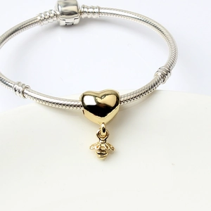 Silver snake chain bracelet featuring a gold heart pendant with a small bee charm