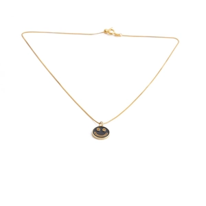 Detailed view of a gold box chain necklace featuring a black round smiley face pendant