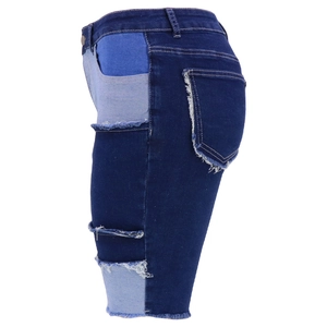 Detail of dark blue denim shorts featuring patchwork design and distressed frayed edges