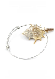 Detailed shot of an adjustable silver stainless steel wire bangle with a sea shell