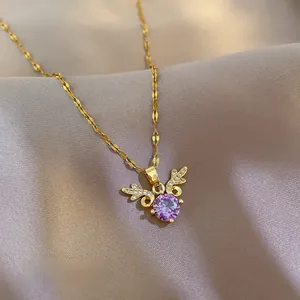 Macro detail of gold-plated necklace with purple zircon stone and winged design