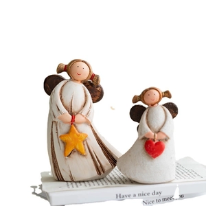 Detail of two resin angels holding a star and heart on a book with rustic hand-painted finish