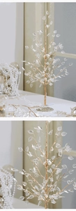 Close-up of glowing acrylic leaves and golden branches of a decorative Christmas tree