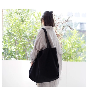 Model view showing the back profile of a large black vintage canvas shoulder bag