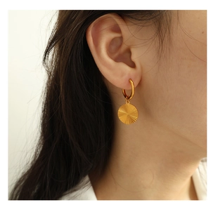 Close-up of golden round sunburst textured earrings worn by a model for detailed view