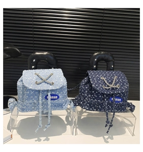 Close-up of sequined denim backpacks in light and dark blue with fashion chains