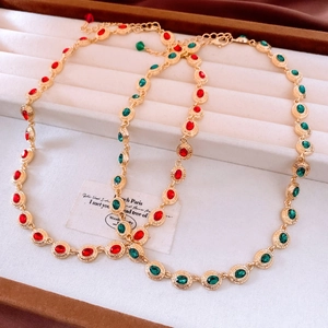 Detail view of vintage oval ruby and emerald necklaces on a beige velvet jewelry tray