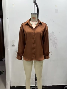 Detailed close-up of brown satin long sleeve shirt featuring elegant ostrich feather cuffs
