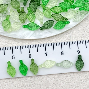 Detailed view of mini green transparent acrylic leaf beads with ruler for size scale