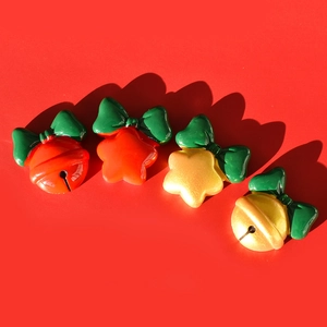 Flat lay of resin Christmas bells and stars with green bows on a red background
