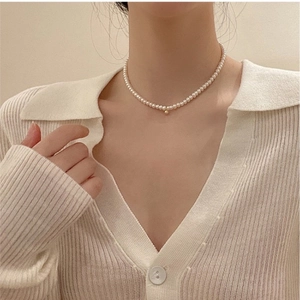 Elegant natural pearl necklace with a minimalist gold bead accent worn by a model
