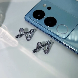 Macro shot of silver wave earrings with micro-paved zircons on a blue phone background
