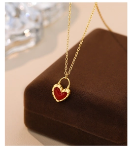 Macro shot of red heart pendant with gold fluted edge in a brown velvet jewelry box