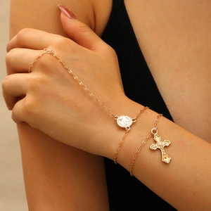 Elegante bracciale anello dorato con medaglia della Madonna e ciondolo a croce sulla mano