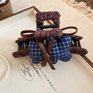 Detail view of the brown fabric hair claw clip with a blue plaid plush bear decoration