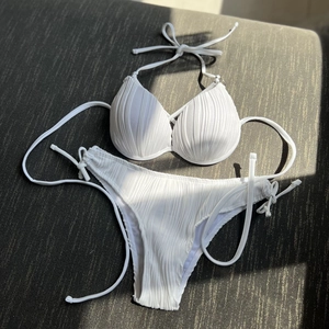 Detail view of white ribbed texture fabric and side-tie strings on a bikini set