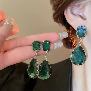 Detailed close-up of emerald green waterdrop earrings with golden alloy settings