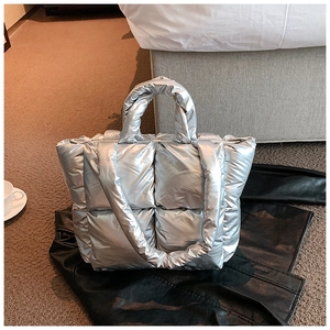 Detail of silver quilted puffer tote bag with metallic finish and soft padded straps
