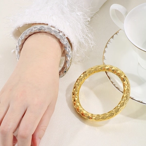 Detailed view of hollow diamond pattern bangles in polished gold and silver finishes