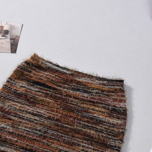 Gros plan détaillé de la jupe trapèze rayée en tweed tons marron orange et noir