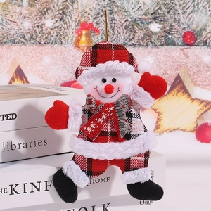 Close-up of plush snowman ornament in red plaid outfit leaning against white books