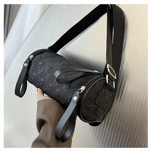 Detail of black cylindrical crossbody bag featuring a unique bubble textured fabric surface