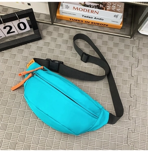 Detail of bright blue waterproof nylon sling bag with orange zipper pull and black strap