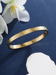 Detailed view of gold plated stainless steel bangle with engraved Roman numerals