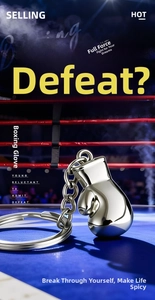 Close-up of a silver polished 3D boxing glove keychain on a realistic boxing ring mat