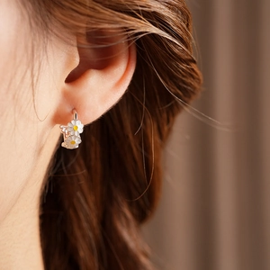 Close-up of vintage enamel daisy flower drop earrings in silver finish on model