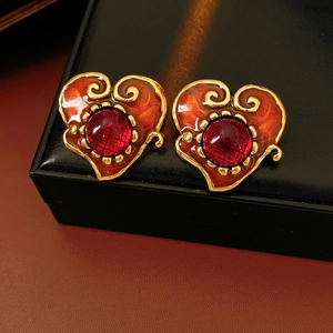 Detail of vintage heart earrings with gold filigree and deep red faceted stone