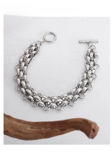 Detail of silver layered chain bracelet with OT toggle clasp on white wood background