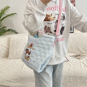 Close-up of quilted light blue shoulder bag with cute puppy embroidery and floral details