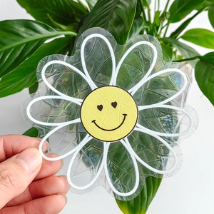 Detailed view of suncatcher sticker with flower shape and yellow smiley face design