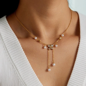 Vintage gold bow necklace with imitation pearls and tassel chain on a model's neck