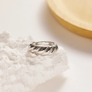 Macro detail of polished silver croissant ring showcasing twisted lava metal texture
