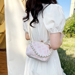 Detail of pink and white shell bag with pearl handle and metal chain on outdoor setting