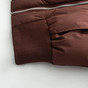 Detail of dark brown hooded parka showing zipper closure and ribbed knit cuffs texture