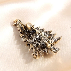 Back view of a Christmas tree brooch in antique gold finish on champagne silk