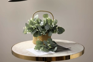 Artificial eucalyptus leaves in a woven basket on a marble table for home decor